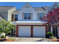 Charming two-story townhouse featuring a two-car garage, brick accents, and a well-manicured front yard on a sunny day at 12407 Crowley Ct, Charlotte, NC 28277