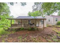 Exterior view of the house featuring a front porch with worn and stained features and landscaping in need of care at 1908 5Th St, Statesville, NC 28677