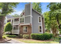 Charming condo featuring a brick facade, neutral siding, lush landscaping, and multi-level balconies at 2502 Cranbrook Ln # 8, Charlotte, NC 28207
