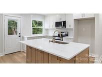 Bright kitchen with white cabinets, stainless steel appliances, and large island with quartz countertop at 4042 Uppergate Ln, Charlotte, NC 28215
