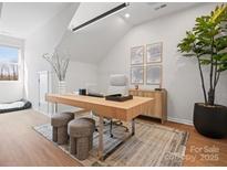 Bright home office featuring a wooden desk, plush stools, natural light, and decorative wall art at 5735 Castlerea Dr, Charlotte, NC 28217