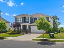 Beautiful two-story home with manicured lawn and attached two car garage under a bright blue sky at 6012 Millbridge Pkwy, Waxhaw, NC 28173