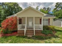 Charming home featuring a covered porch with red shutters and mature landscaping at 772 Austin Rd, New London, NC 28127
