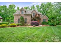 Charming brick home with lush landscaping and mature trees in a serene, picturesque setting at 8216 Malibu Pointe Ln, Denver, NC 28037