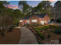 Charming brick home featuring a manicured front yard with lush landscaping and a winding driveway at 961 Confederate Ave, Salisbury, NC 28144