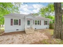 Charming single-story home with light blue siding, dark shutters, and a cozy front porch entrance at 104 Willetta Dr, Charlotte, NC 28217