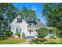 Charming white farmhouse with blue shutters, lush landscaping, and a welcoming front porch at 108 Stockton St, Shelby, NC 28150
