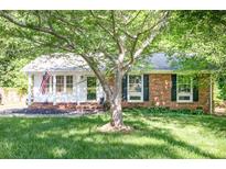 Charming brick home with well-maintained lawn, complemented by mature trees and an American flag display at 1115 Grovewood Dr, Charlotte, NC 28208
