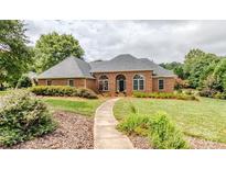 Charming brick home with manicured lawn, arched windows, and a welcoming walkway to the front door at 1337 Braeburn Nw Rd, Concord, NC 28027