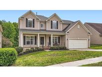 Charming two-story home features a welcoming front porch, manicured lawn, and attached two-car garage at 1455 Moss Creek Dr, Harrisburg, NC 28075