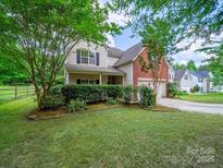 Charming two-story home featuring a manicured lawn, mature trees, and a welcoming front porch at 2020 White Cedar Ln, Waxhaw, NC 28173