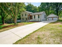 Charming exterior of a modern home with a long driveway and detached garage nestled among mature trees at 437 Chadmore South Dr, Charlotte, NC 28270