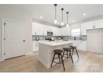 Modern kitchen with white cabinets, stainless steel appliances, and a quartz countertop island with barstool seating at 515 Dixie Dr, Mooresville, NC 28115