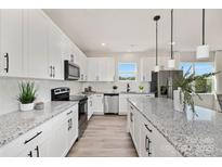 A modern kitchen featuring white cabinets, stainless steel appliances, and a large center island with granite countertops at 515 Dixie Dr, Mooresville, NC 28115