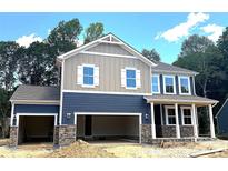 Charming two-story home featuring a two-car garage, stone accents, and a covered front porch at 9945 Cask Way, Huntersville, NC 28078