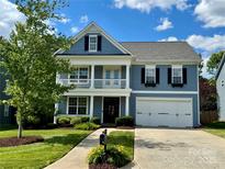 Charming blue two-story home featuring a manicured lawn, a two-car garage and delightful balcony with white railing at 1014 Harrogate Ln, Matthews, NC 28104