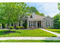 Charming brick home boasts lush lawn, mature trees, and inviting front porch perfect for relaxing at 12039 Lawings Corner Dr, Huntersville, NC 28078
