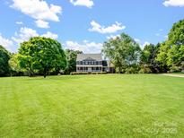 Charming two-story home with front porch and spacious lawn surrounded by mature trees on a sunny day at 4628 Dovefield Ln, Kannapolis, NC 28081