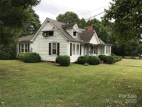 Charming home with tidy landscaping, dark shutters, and a red brick chimney set against a backdrop of mature trees at 609 E Church St, China Grove, NC 28023