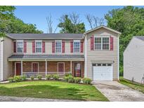 Charming townhome with a welcoming porch and attached garage, surrounded by lush landscaping and mature trees at 6335 Ziegler Ln, Charlotte, NC 28269