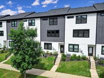 Modern townhome exterior with gray and white siding, black trim, and a well-manicured front lawn and landscaping at 8723 Nolley Ct, Charlotte, NC 28270