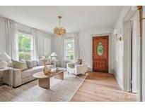 Bright living room with a decorative chandelier, wood front door, and comfortable seating arrangement at 1000 Oakshade Ave, Kannapolis, NC 28083