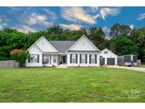 Charming white house features a well-manicured lawn and a detached two-car garage at 1140 Landsdown Dr, Salisbury, NC 28147