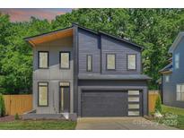Modern two-story home with a gray exterior, attached garage, and minimalist landscaping for sleek curb appeal at 1711 Summey Ave, Charlotte, NC 28205