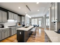 Open kitchen boasts gray cabinets, island with seating, quartz counters, modern lighting, and a breakfast nook at 208 Mcduffie Ln, Fort Mill, SC 29715