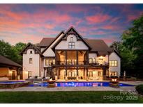 Luxury home featuring a large backyard with a pool, fire pits, and patio under a covered porch at sunset at 2288 Brawley School Rd, Mooresville, NC 28117