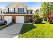 Charming two-story townhome with manicured lawn, attached garages, and inviting curb appeal on a sunny day at 3129 Summerfield Ridge Ln, Matthews, NC 28105