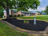 Charming brick home featuring a well-manicured lawn, fresh mulch, and lush landscaping at 404 Kings Dr # 7, Cherryville, NC 28021