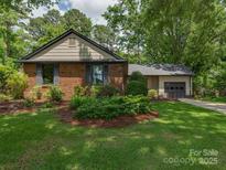 Charming brick home featuring a well-manicured lawn and mature landscaping at 6001 Charing Pl, Charlotte, NC 28211