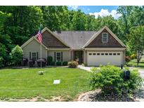 Charming single-story home with mature landscaping, an American flag, and a two-car garage at 6398 Winding Creek Ln, Denver, NC 28037