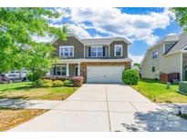 Two story home with neutral siding, brick accents, landscaping and two car garage at 7711 Kelburn Ln, Charlotte, NC 28273