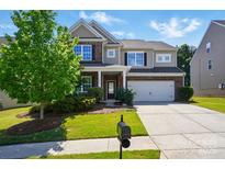 Charming two-story home boasts a brick and siding exterior, attached two-car garage, and a well-manicured front yard at 9301 Swimming Dr, Harrisburg, NC 28075