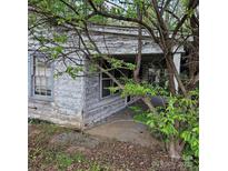 Distressed exterior with peeling paint, overgrown landscaping, and a covered porch at 1015 Frederick St, Shelby, NC 28150