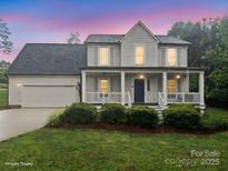 Charming two-story home with a covered porch, lush landscaping, and an attached two-car garage at 10749 Kingsview Dr, Davidson, NC 28036