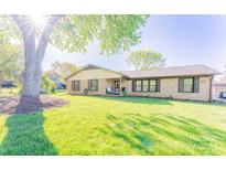 Charming brick home featuring a well-manicured lawn and mature shade tree at 125 Southwood Park, Mooresville, NC 28117