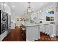 Bright, all-white kitchen with stainless steel appliances, granite countertops, and a large center island with seating at 15247 Prescott Hill Ave, Charlotte, NC 28277