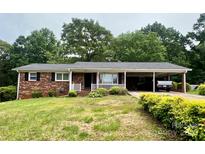 Charming brick home featuring a carport and a cozy front porch surrounded by lush landscaping at 157 E Meadowview Dr, Statesville, NC 28625