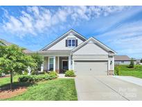 Charming home with a two-car garage, landscaped yard and a cozy porch under a sunny blue sky at 174 Hanks Bluff Dr, Mooresville, NC 28117