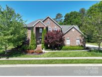 Charming two-story brick home with well-manicured lawn, mature trees, and lovely landscaping at 201 Vanderbilt Blvd, Locust, NC 28097