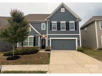 Charming two-story home with a blue facade, black shutters, attached two-car garage, and tidy landscaping at 3022 Burnello Ct, Iron Station, NC 28080
