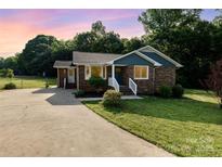 Charming brick home with blue siding accents, landscaped yard, and a concrete driveway at sunset at 3555 Tree Line Dr, Rock Hill, SC 29732