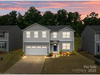 Charming two-story home showcasing manicured landscaping and an inviting facade under a vibrant twilight sky at 703 Pointe Andrews Dr, Concord, NC 28025