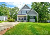 Charming two-story home with gray siding, black shutters, a lush green lawn, and mature trees at 8024 Eagle St, Mount Pleasant, NC 28124
