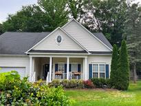 Charming one-story home featuring a inviting front porch, lush landscaping and timeless architectural details at 11647 Baystone Pl, Concord, NC 28025