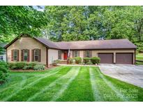 Charming single-story home with a well-manicured lawn, a two-car garage, and beautiful mature trees at 14027 Springwater Dr, Matthews, NC 28105
