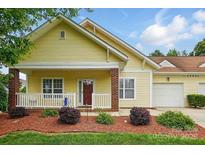 Charming yellow home with inviting front porch, manicured landscaping, and attached garage at 2323 Granville Pl # A, Monroe, NC 28110